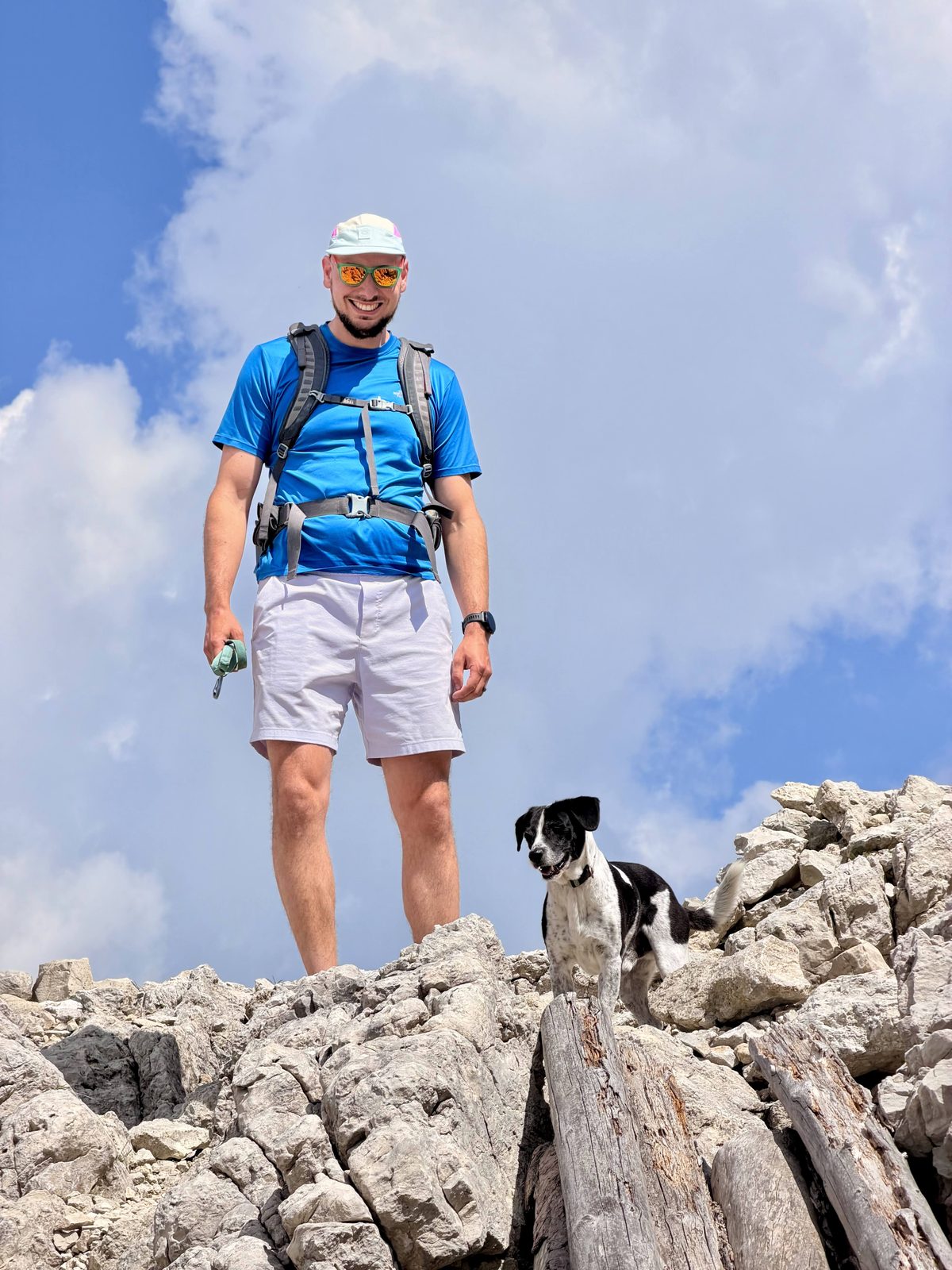David Rokhinson standing on a rocky summit with a black-and-white dog